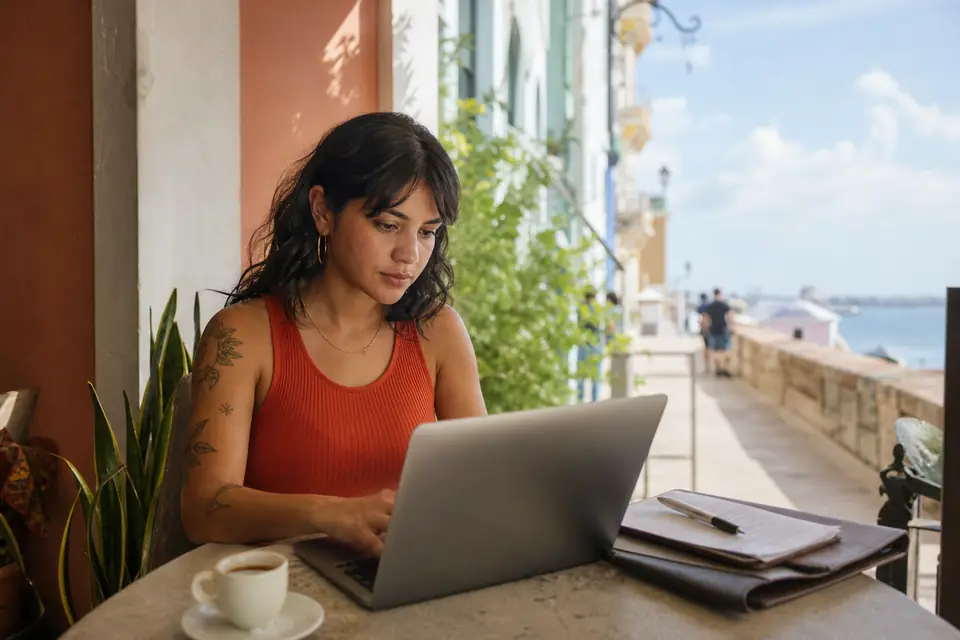 Diseñadora gráfica trabaja por cuenta propia en su computadora en un café.