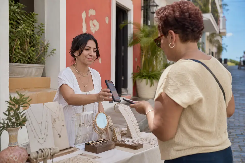 Artesana vende prendas en una feria de artesanías y cobra con el celular